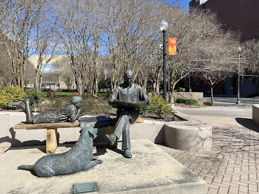 statue of man and dog seated on a bench in a park